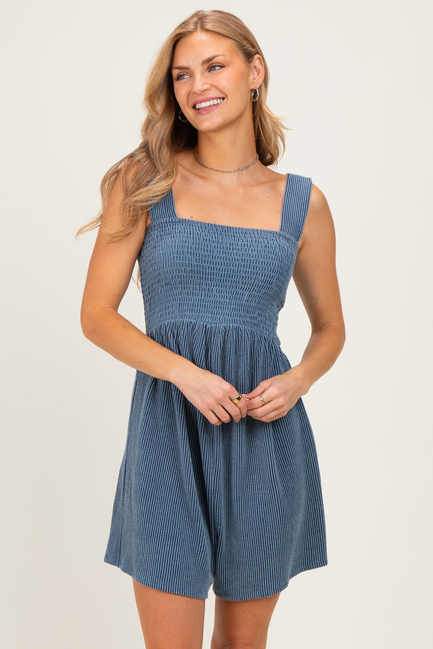 woman wearing a blue smocked mini dress with square neckline and adjustable straps