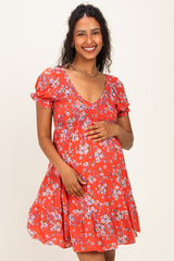 woman wearing a red floral maternity dress with short puff sleeves and a fitted bodice, holding her baby bump