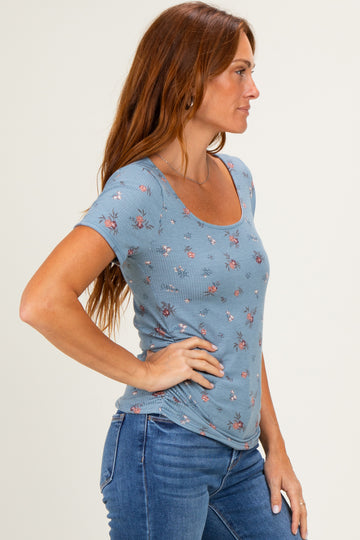 woman wearing a light blue short sleeve floral top with a scoop neckline and side view profile