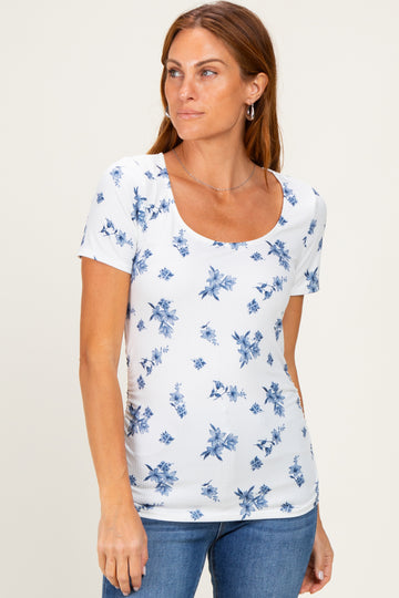 woman wearing a white short sleeve top with blue floral print and a scoop neck, paired with denim jeans