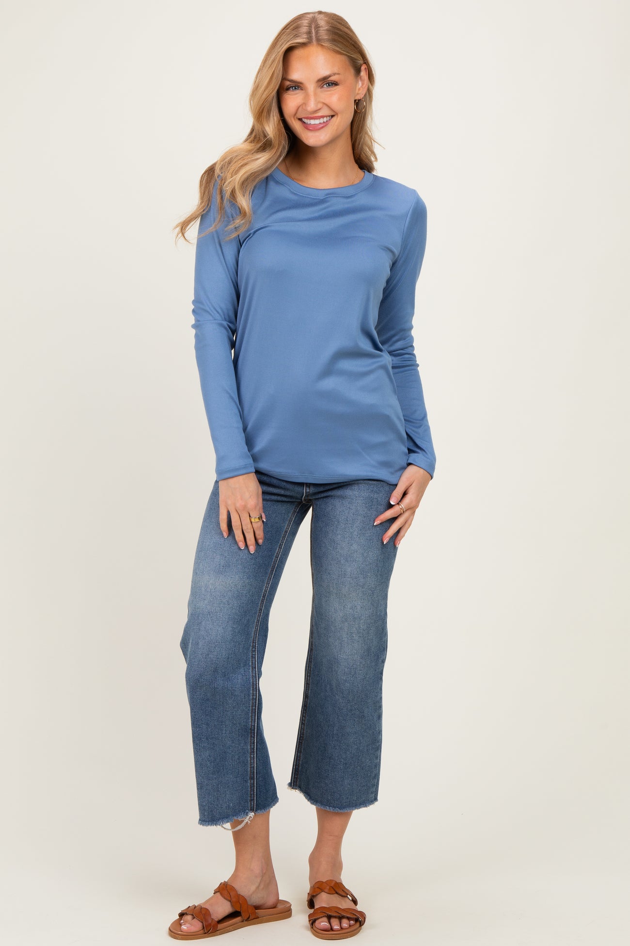 woman wearing a light blue long sleeve top paired with wide leg cropped jeans and brown sandals