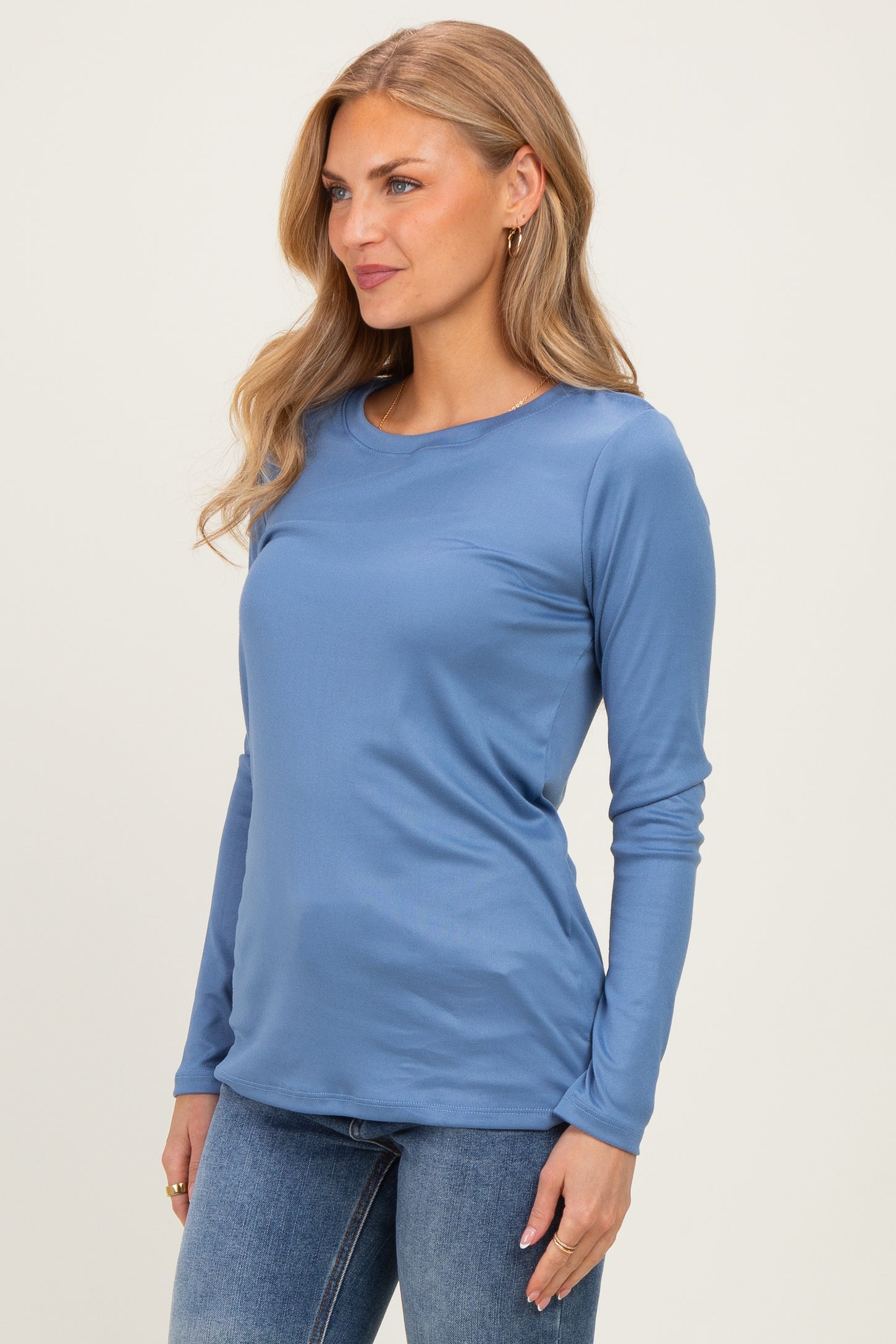 woman wearing a blue long sleeve top with a round neckline and fitted style, paired with jeans