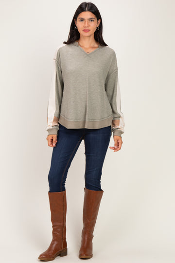 woman wearing a light green long sleeve pullover sweater with cream accents and blue skinny jeans, paired with brown knee-high boots