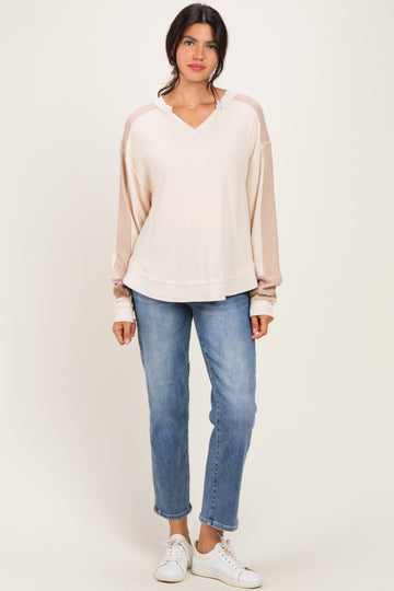 woman wearing a light pink long sleeve hoodie paired with blue jeans and white sneakers