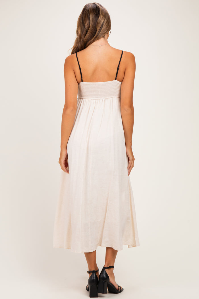 woman wearing a tan maternity maxi dress with a smocked bodice and adjustable spaghetti straps, showing her baby bump