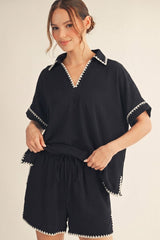 woman wearing a black short sleeve pullover top with white trim and matching black shorts with an elastic waistband