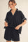 woman wearing a black short sleeve pullover top with white trim and matching black shorts with an elastic waistband
