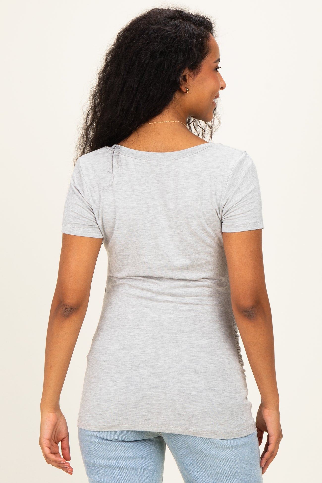 woman wearing a light gray short sleeve maternity top, showing a fitted style from the back