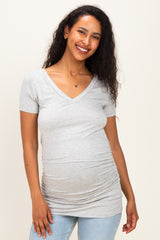 woman wearing a gray short sleeve maternity top with ruching at the sides and a v-neckline, displaying her baby bump