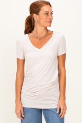 woman wearing a light pink short sleeve v-neck top with side ruching and casual blue jeans