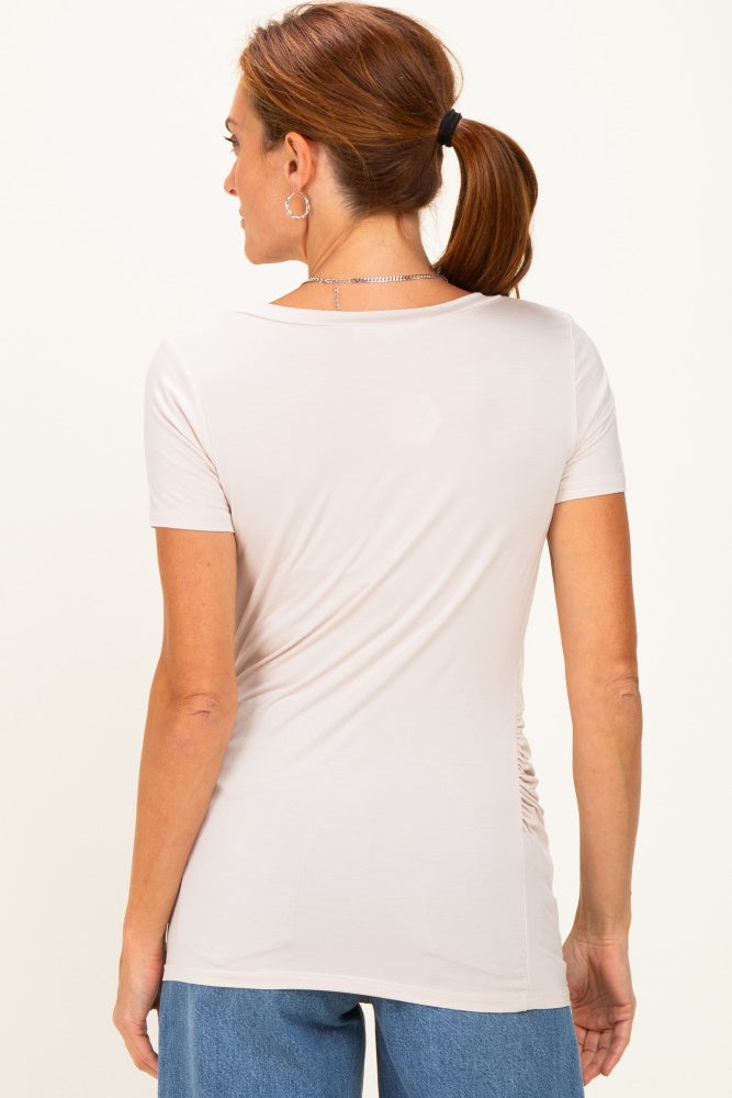 woman wearing a light beige short sleeve top with ruching detail on the back and blue denim jeans