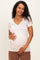 woman wearing a light beige short sleeve maternity top and holding her baby bump