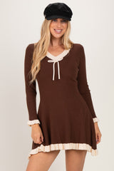 woman wearing a brown long sleeve ribbed dress with a scalloped neckline and ruffled hem details