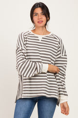 woman wearing a gray and white striped oversized sweater with side slits and long sleeves, paired with blue jeans