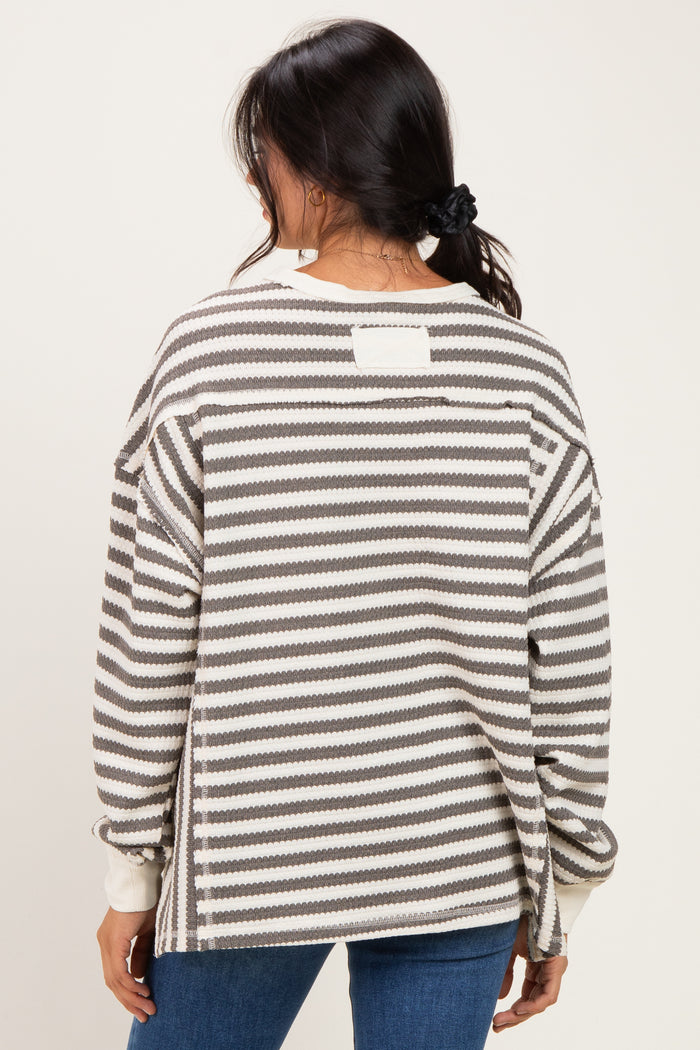 woman wearing a gray and white striped oversized sweater, shown from the back, with a relaxed fit and drop shoulder design
