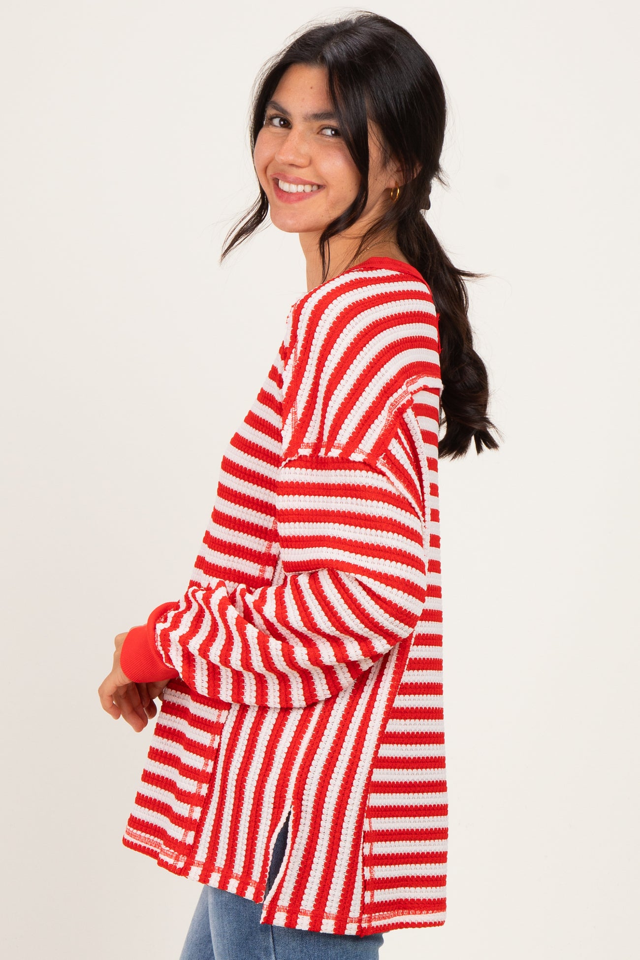 woman wearing a red and white striped oversized sweater with side slits and long sleeves