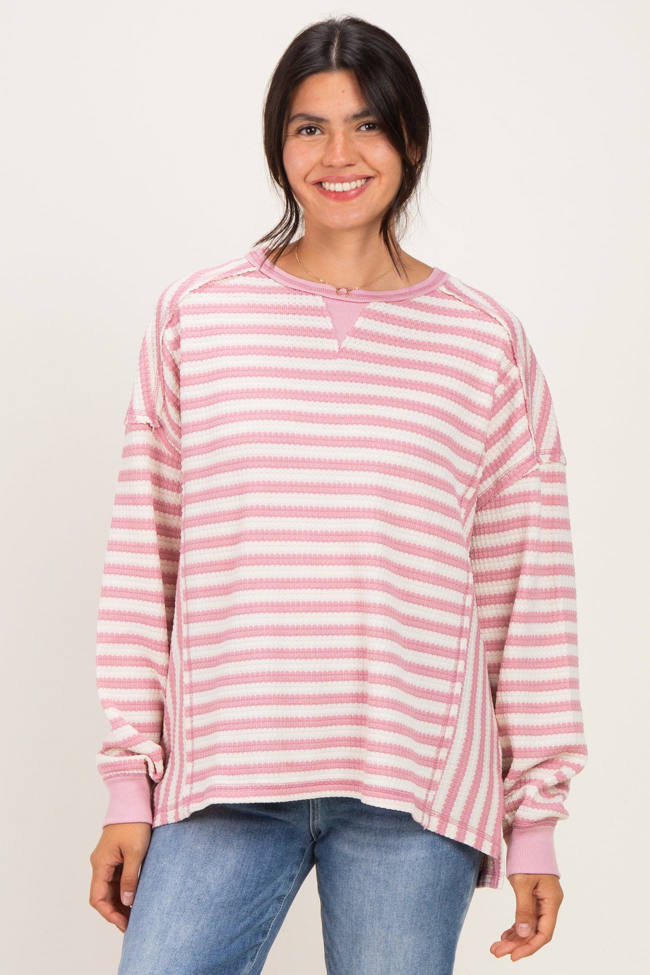 woman wearing a pink and white striped oversized sweatshirt with a relaxed fit and long sleeves