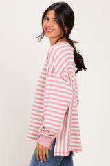 woman wearing a pink and white striped oversized sweatshirt with long sleeves and a relaxed fit