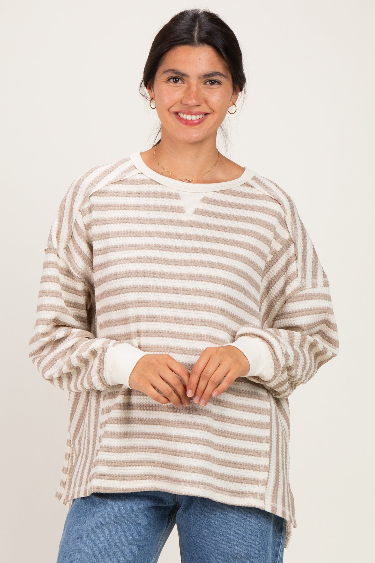 woman wearing a cream and beige striped oversized sweatshirt with a crew neckline and long sleeves