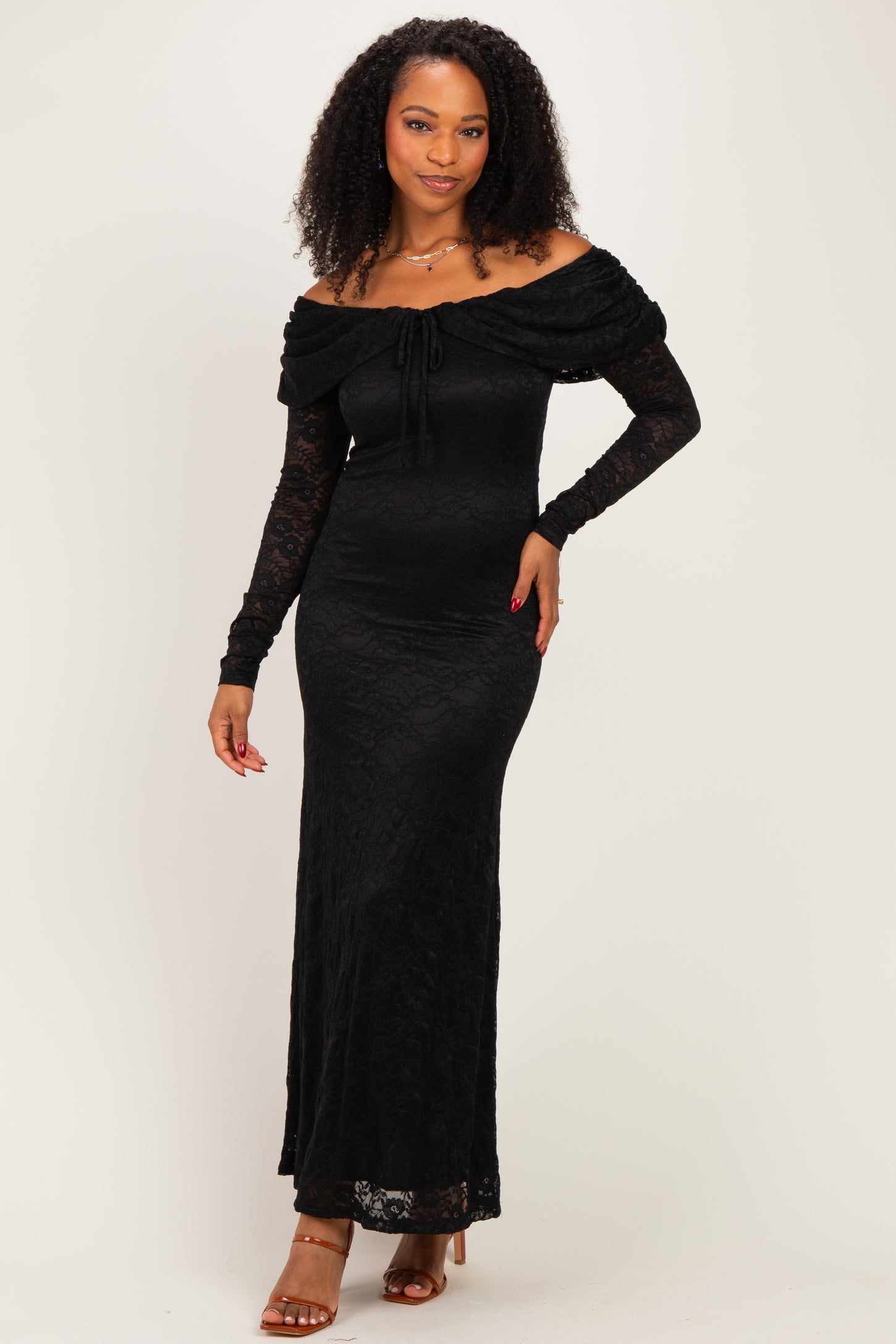 woman wearing a black off-the-shoulder lace maxi dress with long lace sleeves and a tie detail on the bust