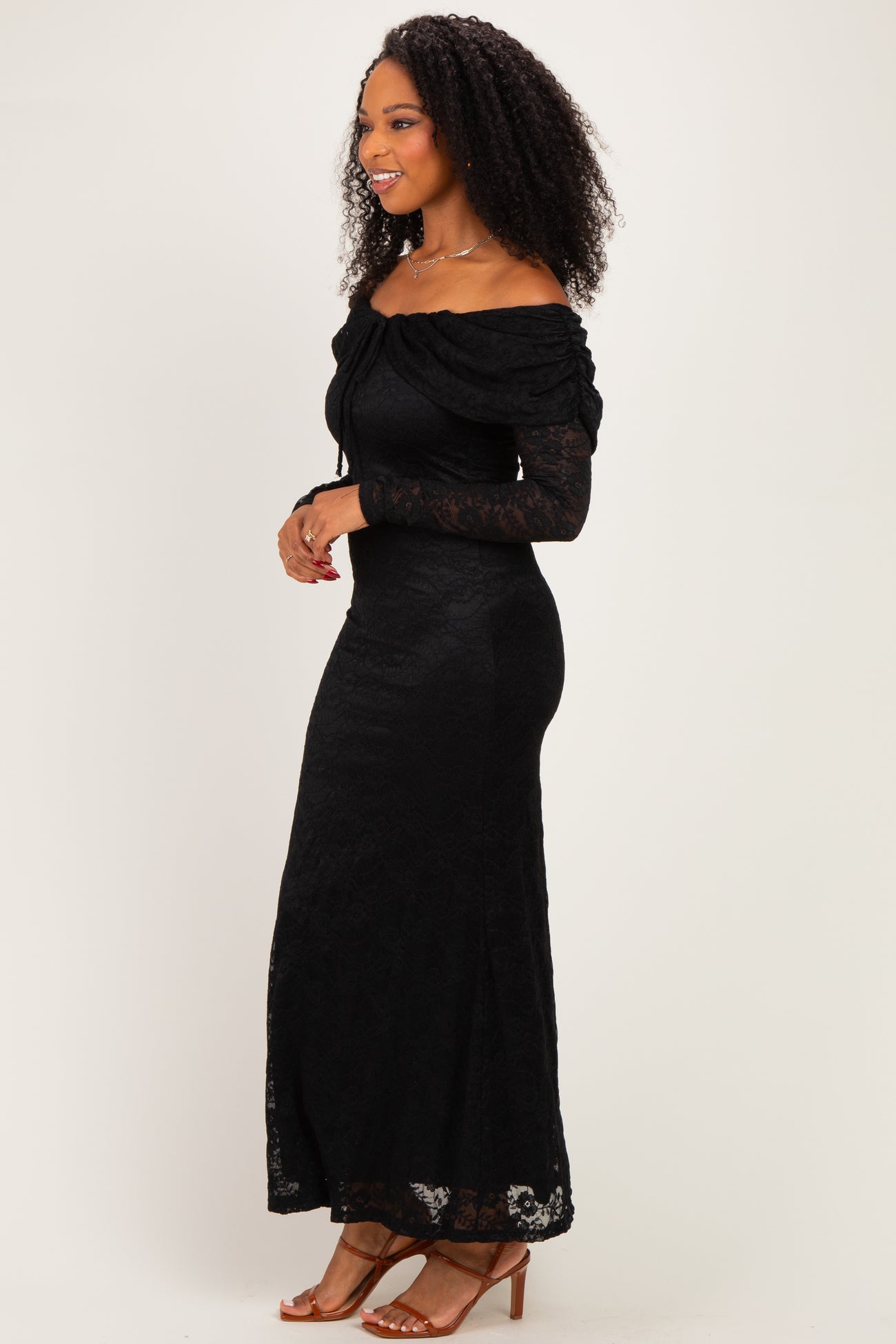 woman wearing a black off-the-shoulder lace maxi dress with long sleeves and fitted silhouette