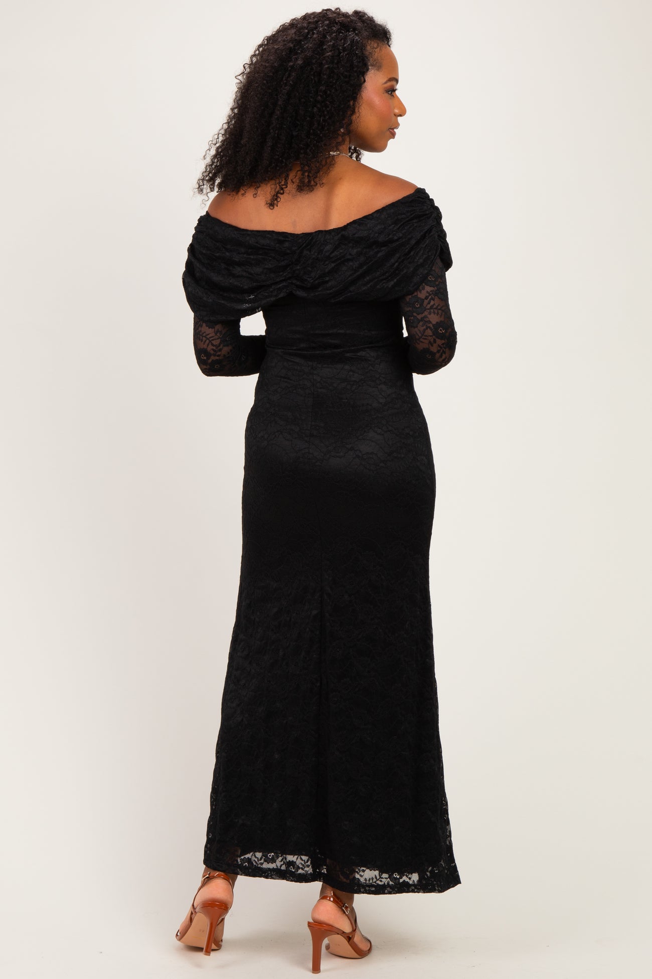woman wearing a black off-the-shoulder lace gown with long sleeves and a fitted silhouette, viewed from the back