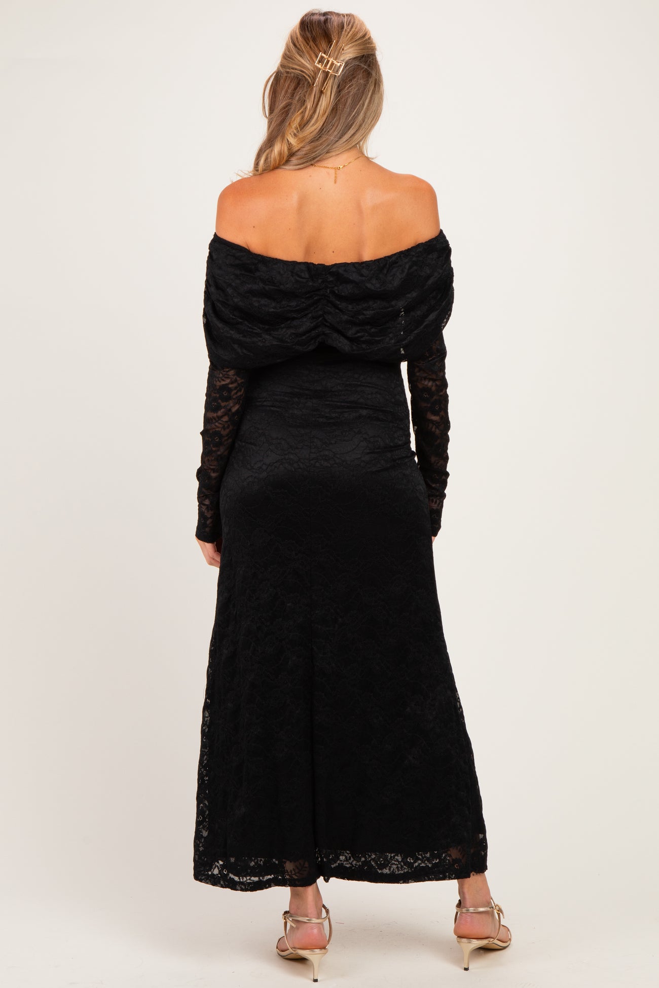 woman wearing a black off-shoulder lace maternity dress with long sleeves and a fitted bodice