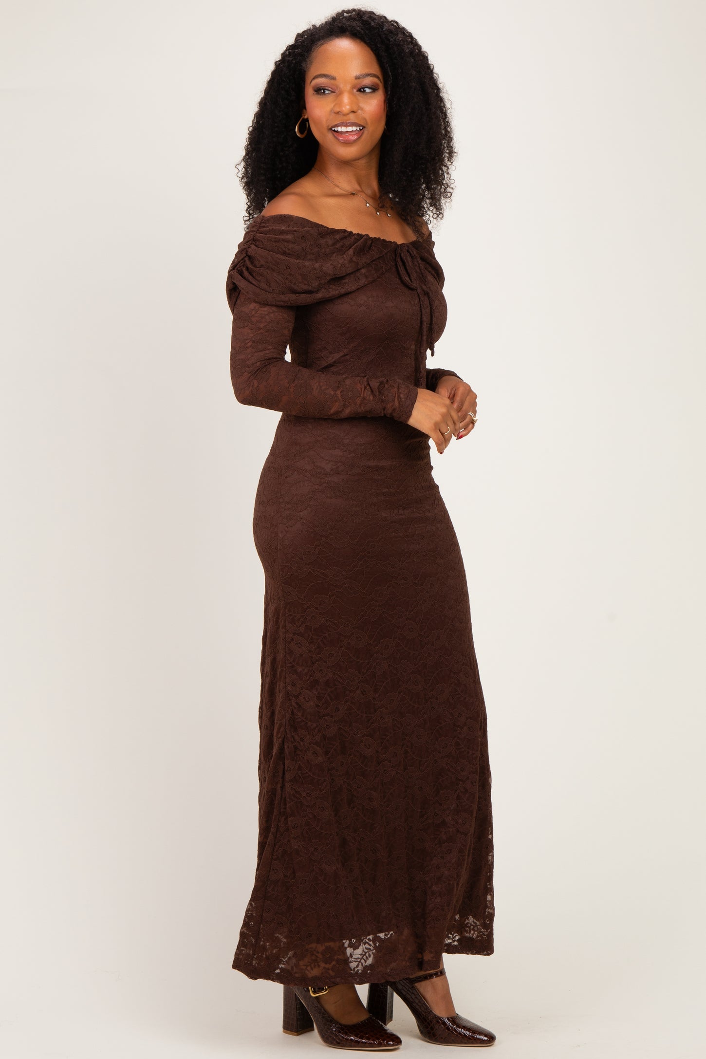 woman wearing a brown off-the-shoulder lace maxi dress with a fitted silhouette and long sleeves