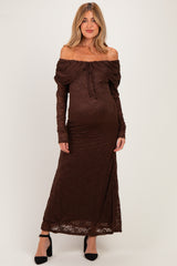 woman wearing a brown off-the-shoulder lace maternity dress with a fitted silhouette and long sleeves, showcasing her baby bump