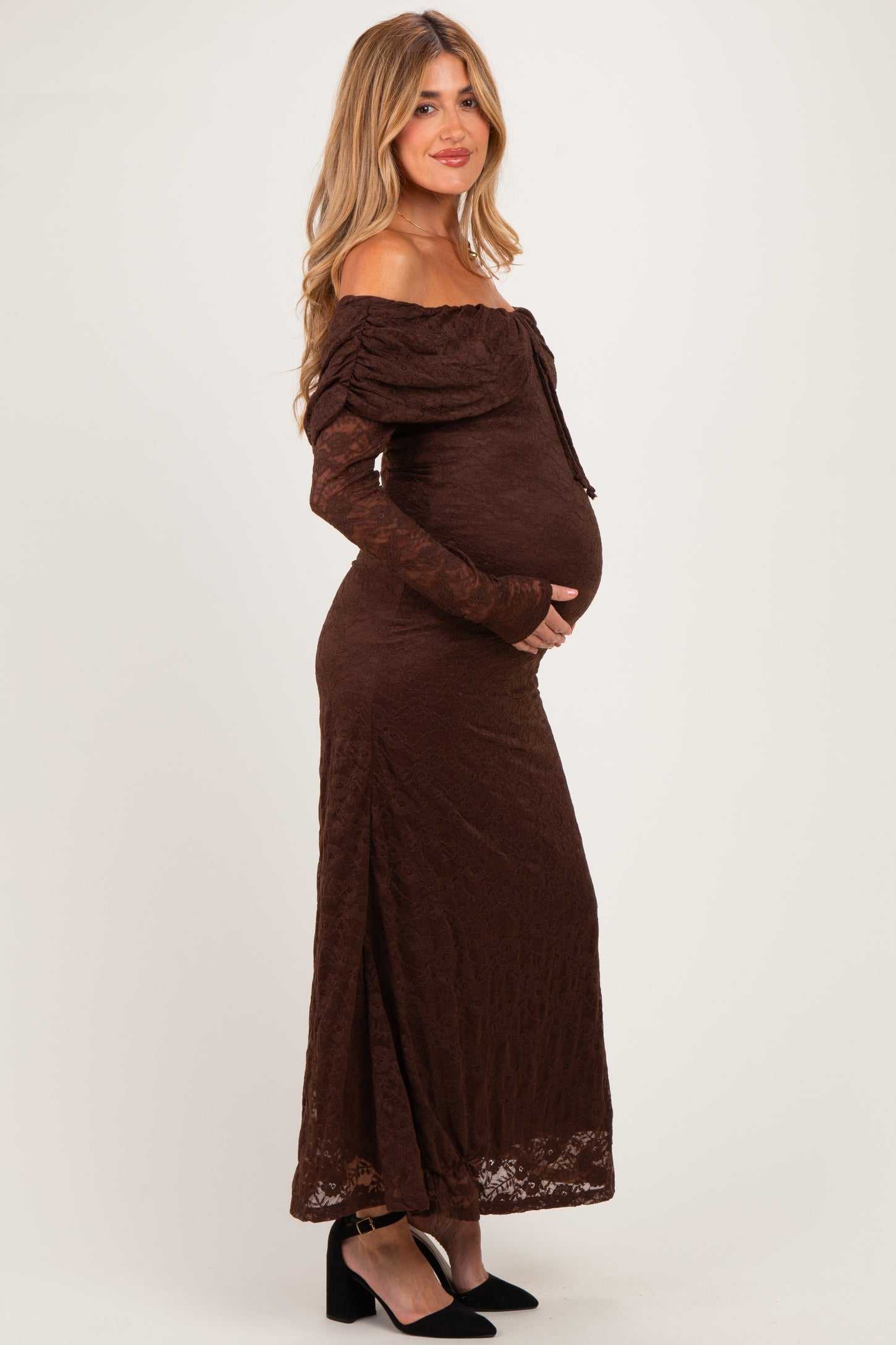 woman wearing a brown lace off-the-shoulder maternity dress, showcasing her baby bump