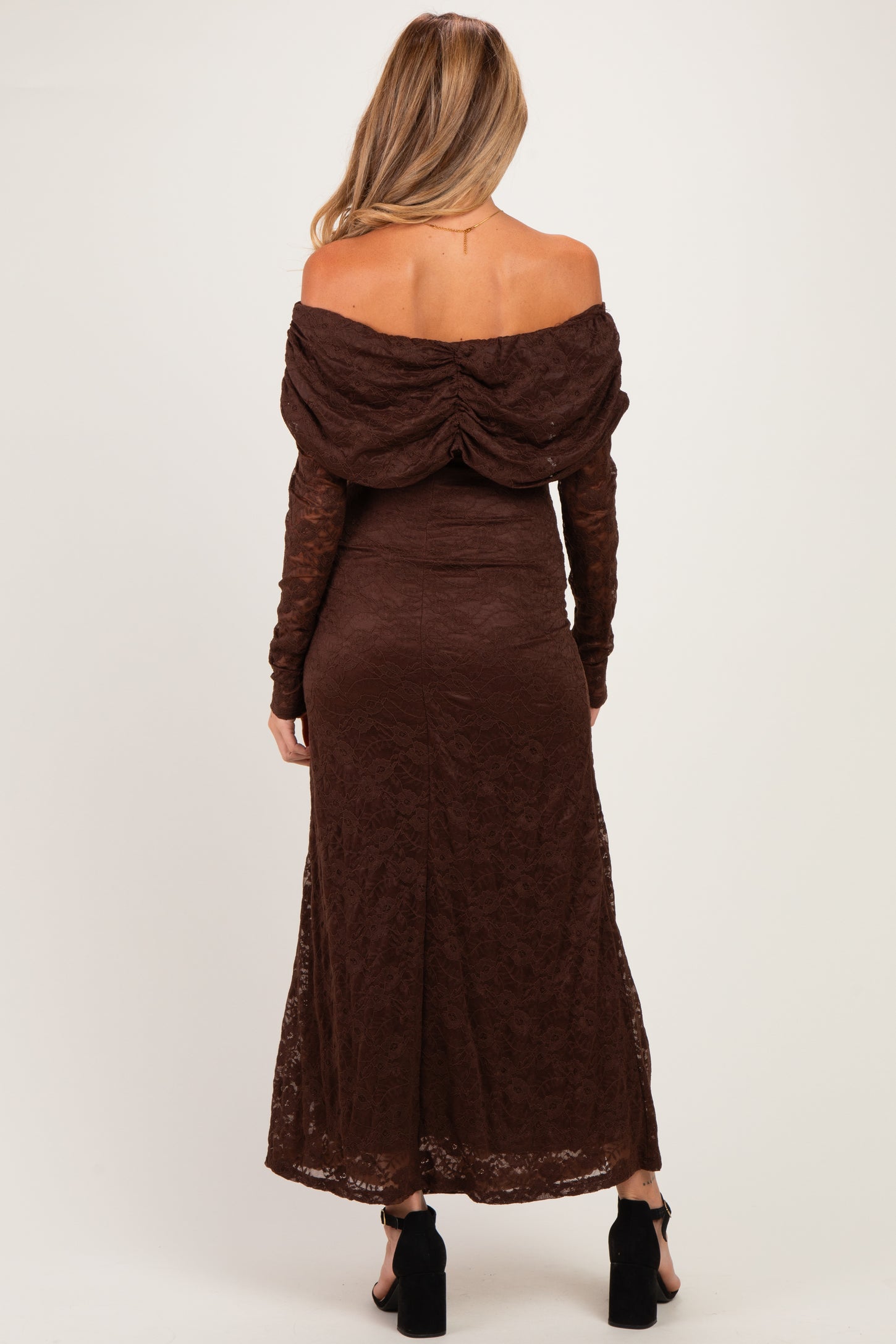 woman wearing a brown off-the-shoulder lace maternity dress with a flowing skirt and long sleeves