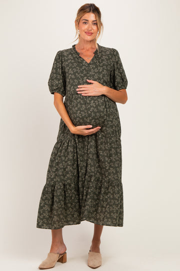 woman wearing a dark green floral maternity maxi dress and holding her baby bump