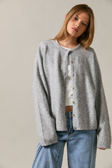 woman wearing a light gray button-up cardigan layered over a white top and paired with high-waisted jeans