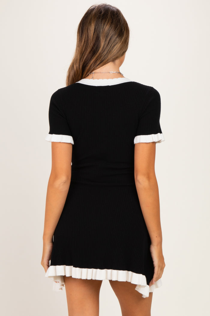 woman wearing a black ribbed maternity dress with white ruffled hem and sleeves, showcasing a baby bump
