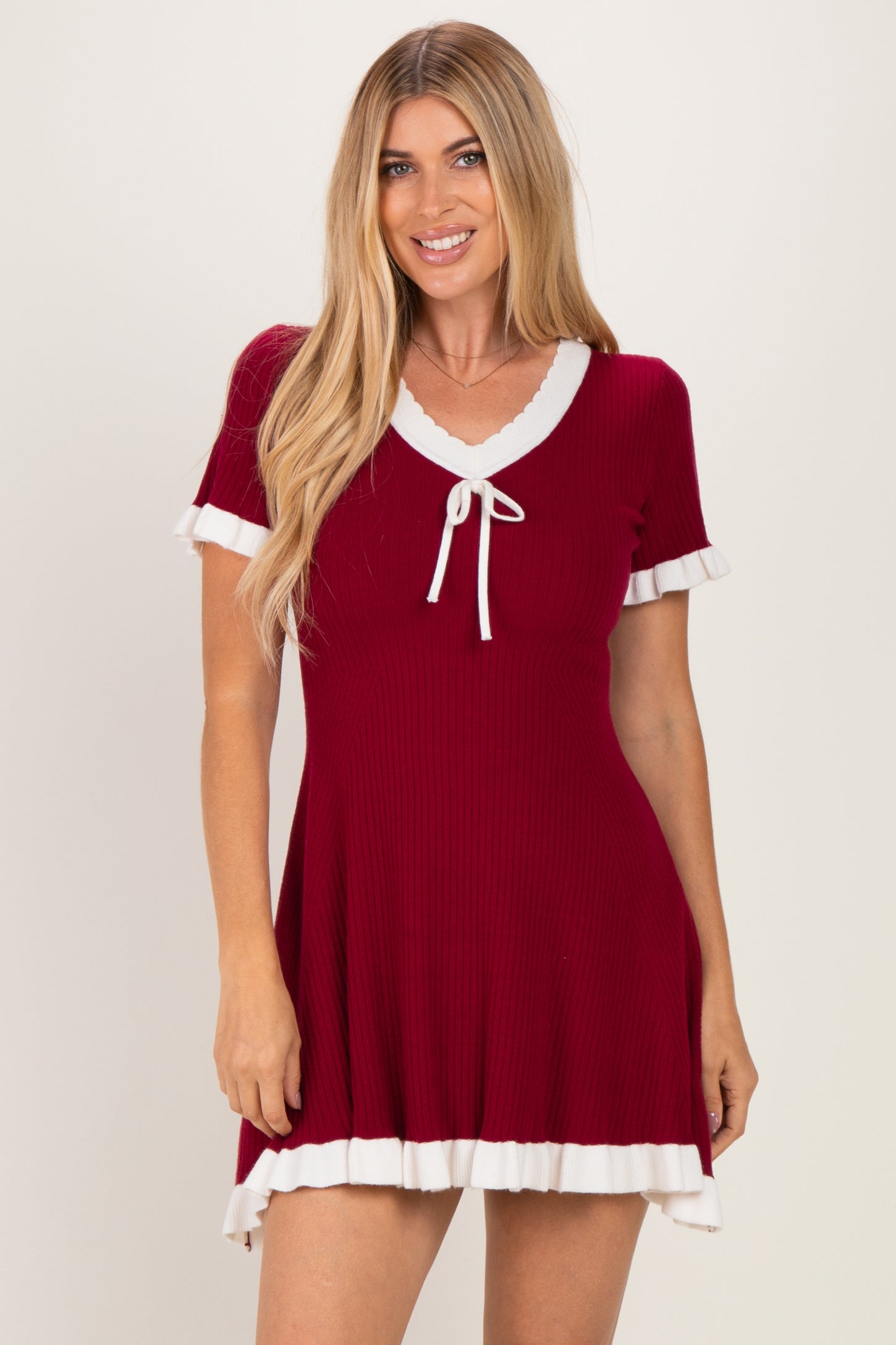 woman wearing a red short sleeve dress with white ruffle trim and a tie neckline