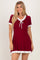 woman wearing a red short sleeve dress with white ruffle trim and a tie neckline