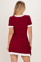 woman wearing a red ribbed dress with white ruffle details on the sleeves and hem, shown from the back