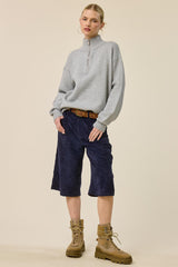 woman wearing a gray zip-up sweater and navy corduroy culottes with tan combat boots