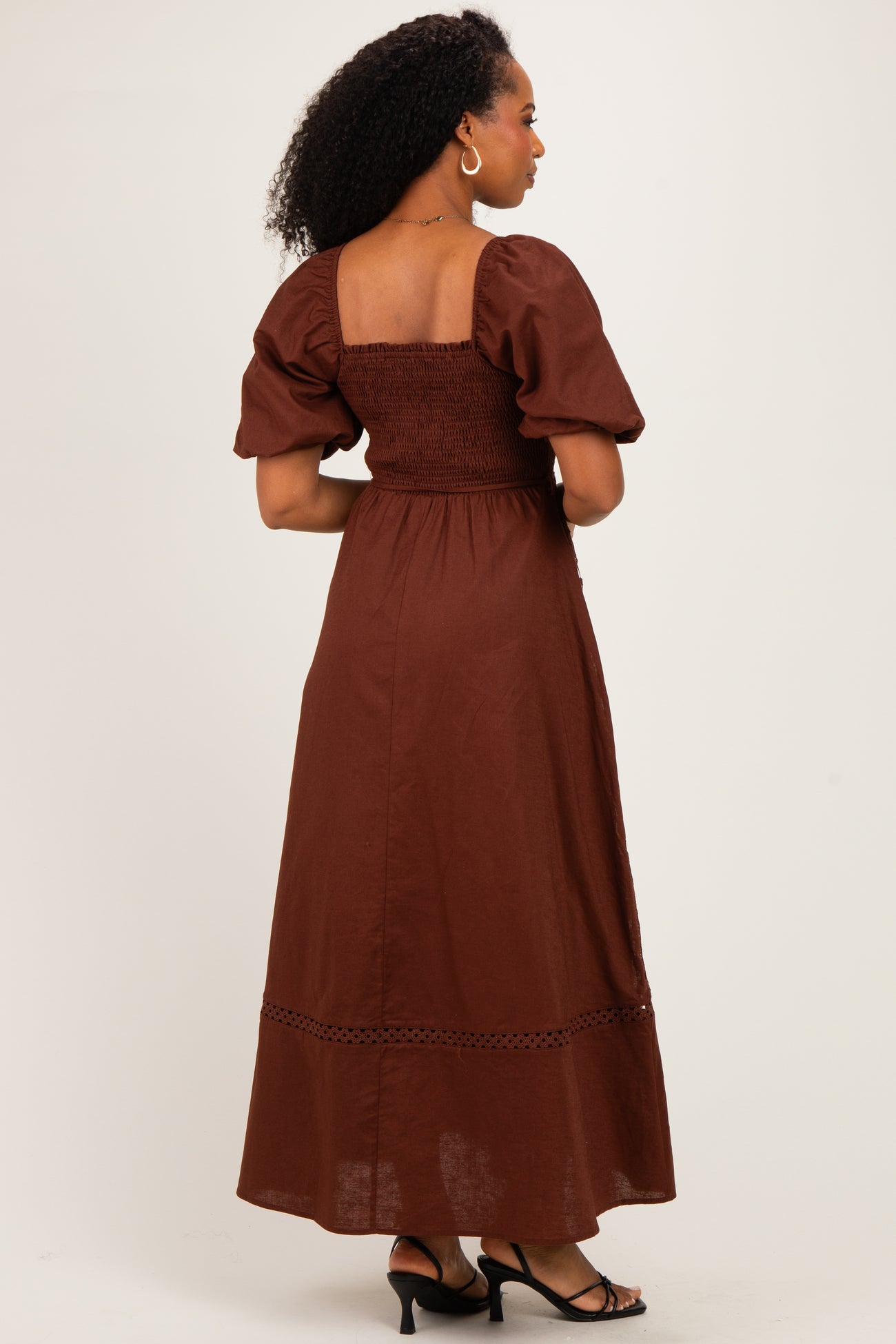 woman wearing a brown puff sleeve smocked maxi dress with a tiered hem and open back detail
