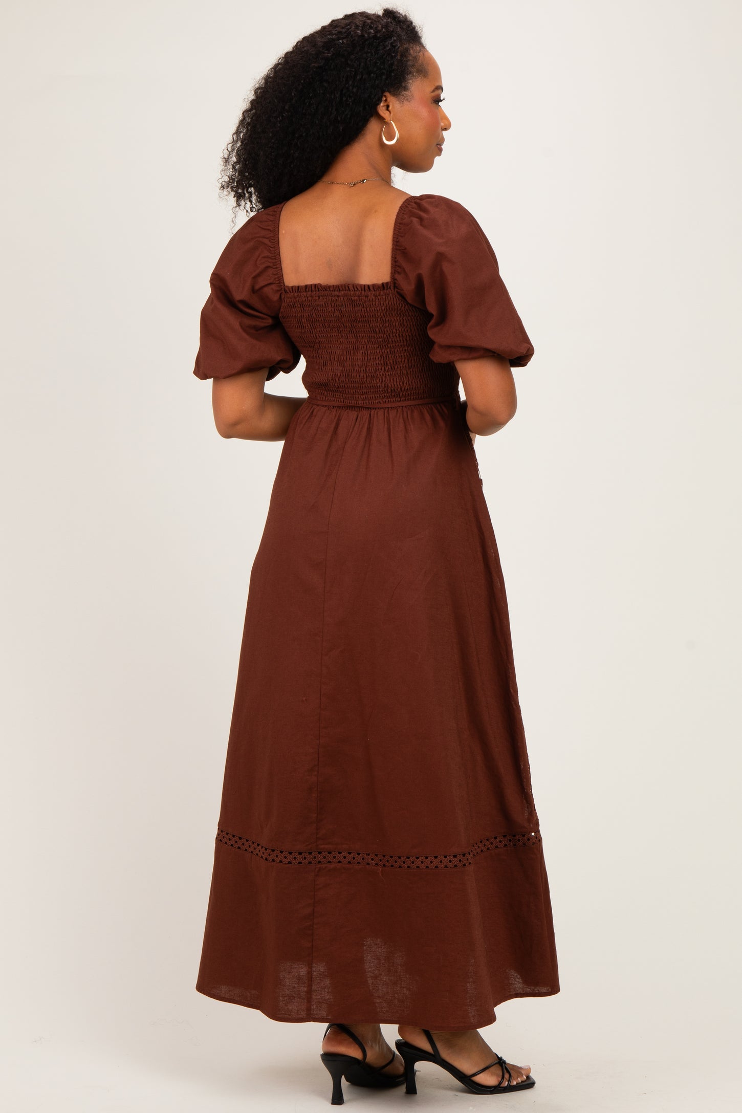 woman wearing a brown puff sleeve smocked maxi dress with a tiered hem and open back detail