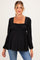 woman wearing a black maternity top with a square neckline and long sleeves, showing her baby bump while smiling