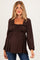 woman wearing a dark brown maternity top with a square neckline and long sleeves, showcasing her baby bump