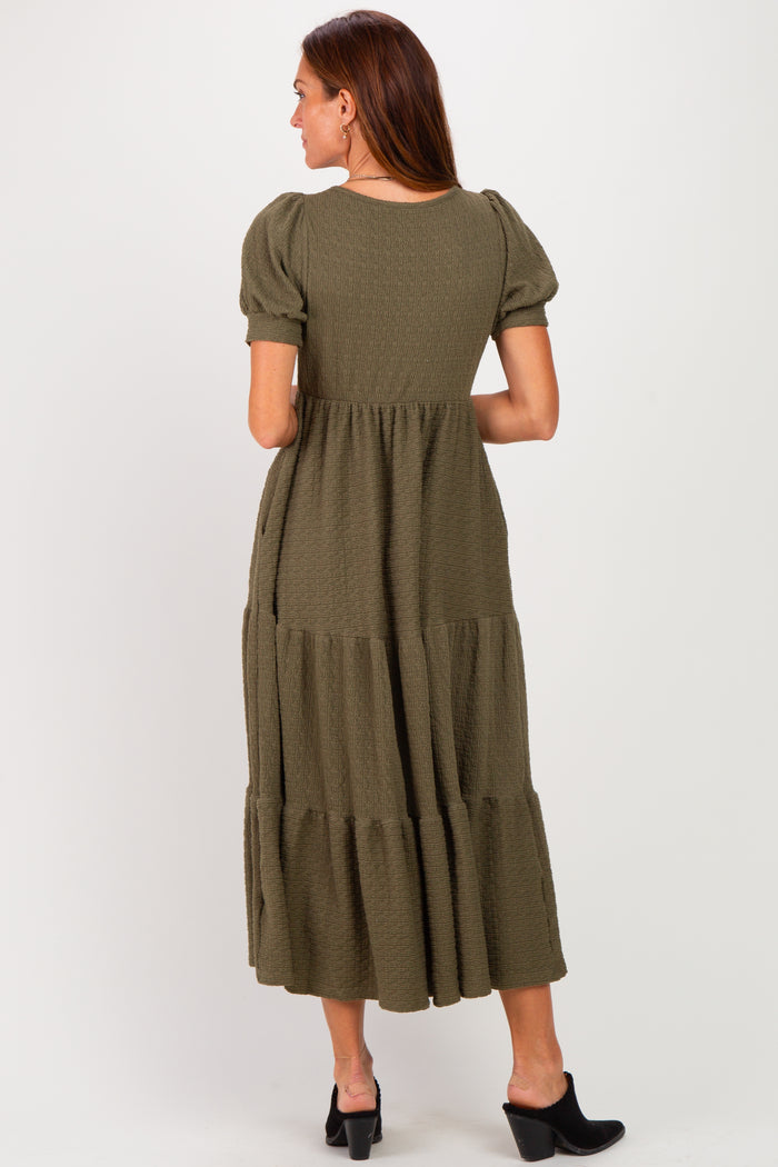 woman wearing an olive green maxi dress with puff sleeves and a tiered skirt, shown from the back
