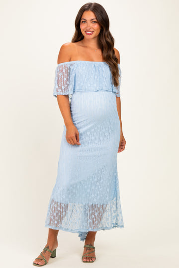 woman wearing a light blue off-the-shoulder maternity dress with sheer lace details and a visible baby bump