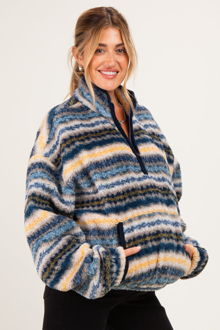 woman wearing a striped fleece maternity pullover with a quarter zip and front pockets, holding her baby bump