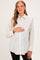 woman wearing a cream maternity button-up shirt with black polka dots and holding her baby bump