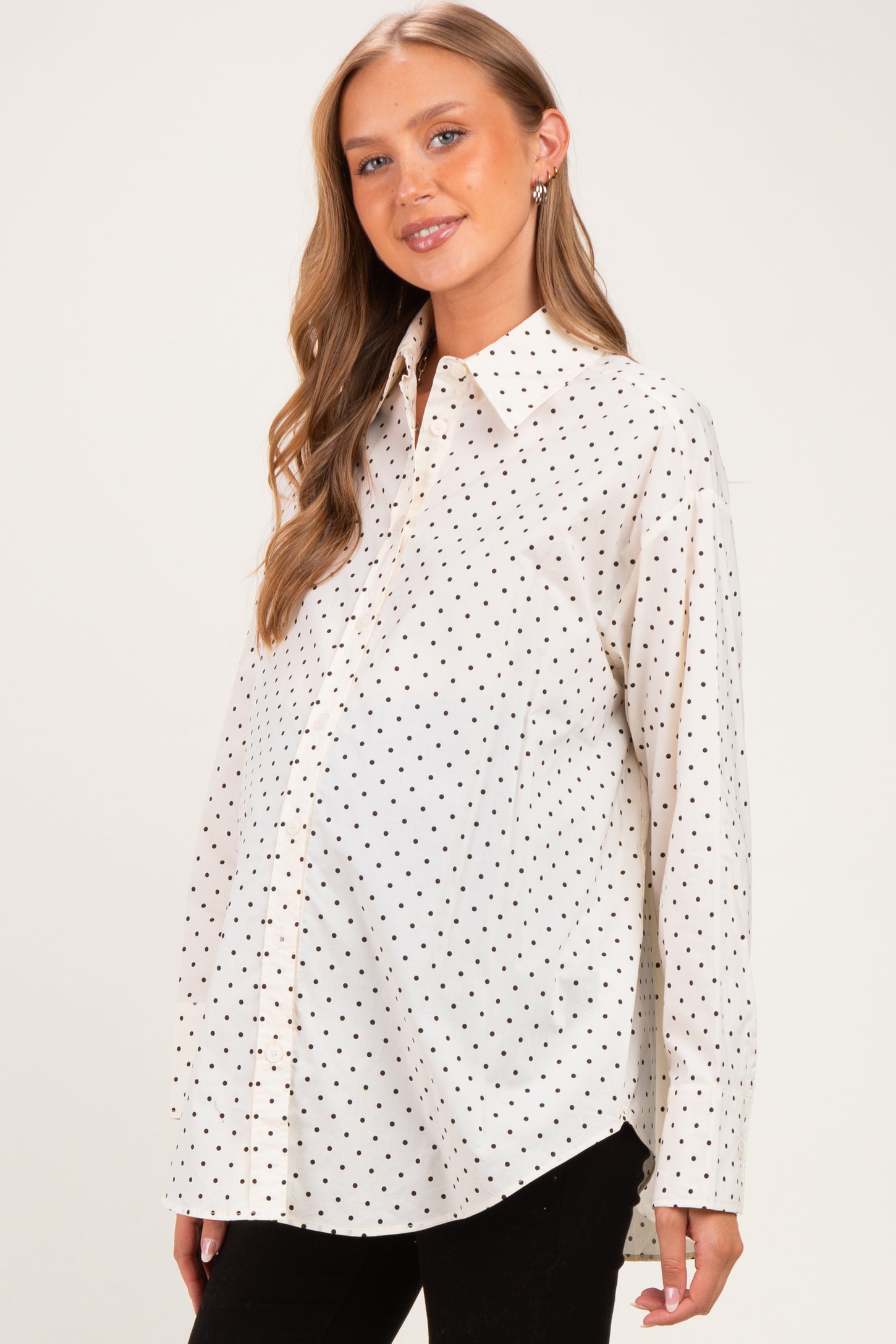 woman wearing a white maternity shirt with black polka dots and a visible baby bump