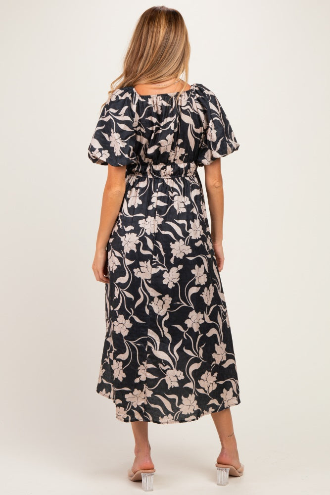 woman wearing a floral patterned black maternity dress with puff sleeves and an elastic waist, seen from the back