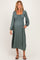 woman wearing a green maternity dress with a square neckline, long sleeves, and a visible baby bump