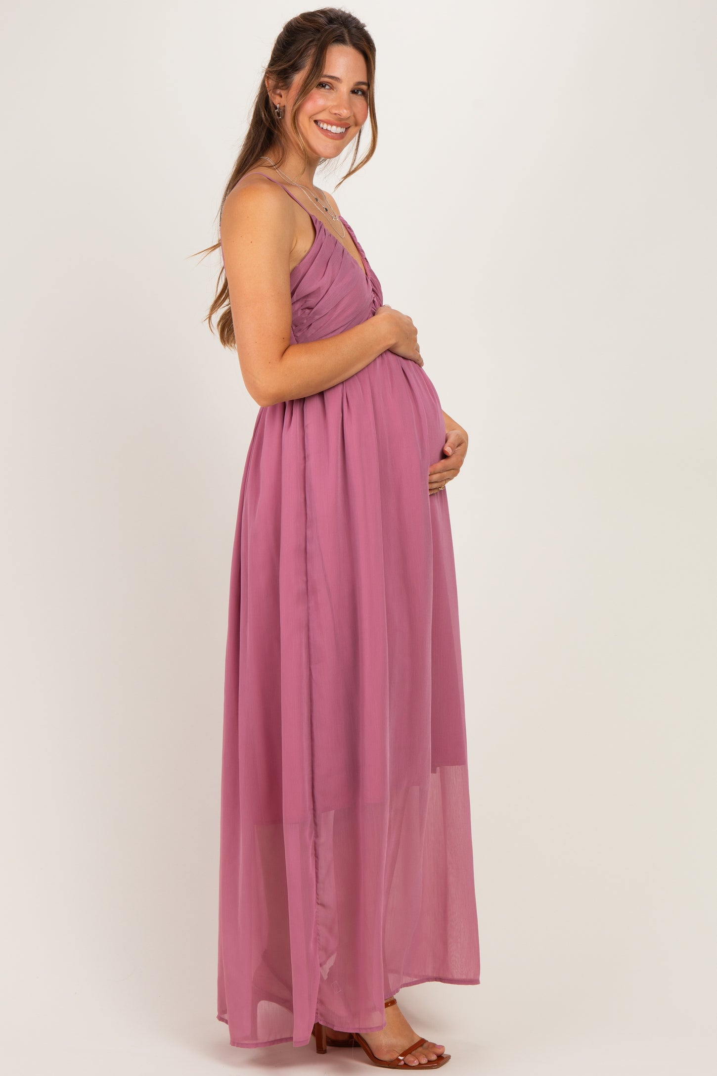 woman wearing a flowy mauve maternity dress with a full skirt and holding her baby bump